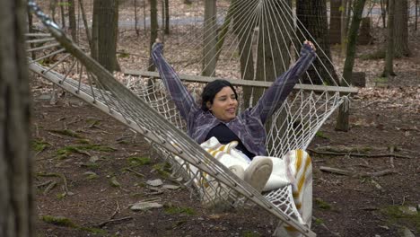 Peaceful-young-female-swinging-in-woodland-hammock-having-relaxed-lazy-time-alone