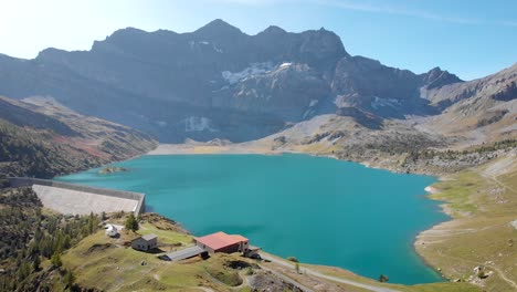 Sobrevuelo-Aéreo-Sobre-Las-Costas-Y-El-Agua-Del-Lago-De-Salanfe-En-Valais,-Suiza-En-Un-Soleado-Día-De-Otoño-En-Los-Alpes-Suizos-Con-Vistas-A-Los-Picos-Alpinos,-Acantilados-Y-Represa-Hidroeléctrica