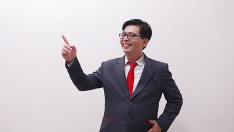 Joyful-asian-businessman-in-suit-standing-while-pointing-both-sides-on-right-and-left