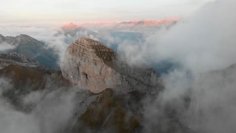 Hyperlaser-Luftaufnahme-Der-Tour-De-Mayen-Und-Tour-D&#39;Aï-In-Leysin,-Waadt,-Schweiz-Mit-Wolken,-Die-An-Den-Berggipfeln-Und-Klippen-Vorbeiziehen,-Mit-Einem-Farbenfrohen-Alpenglühen-Auf-Den-Schweizer-Alpen-Im-Hintergrund