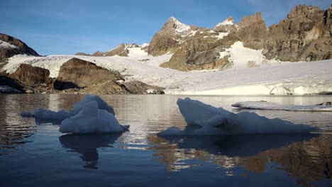 Tranquila-Escena-Matutina-En-El-Lago-Glacial-Junto-Al-Glaciar-Claridenfirn-En-Uri,-Suiza,-Con-Los-Picos-Alpinos-Reflejados-Y-Los-Icebergs-Flotando-En-Primer-Plano
