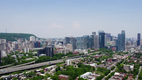 Aerial-tracking-shot-in-front-of-the-skyline-of-sunny-Montreal,-Quebec,-Canada