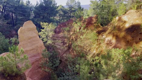 Valley-of-ocher-rocks-that-can-also-be-used-for-painting-as-pigments,-strongly-colored-ground,-in-the-evening-with-many-beautiful-trees-and-sunset