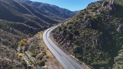 Drone-Flying-over-Curvy-Road-in-Between-Mountains