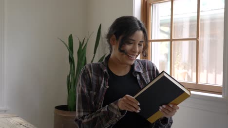 Pleased-Puerto-Rican-female-looking-at-camera-smiling-in-adoration-of-her-new-reading-book