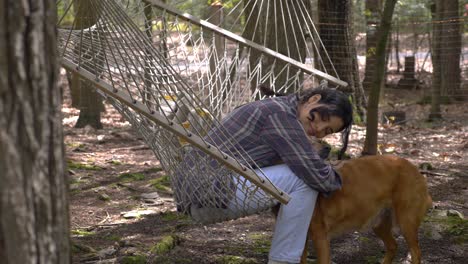 Glückliches-Puertoricanisches-Mädchen,-Das-In-Der-Waldhängematte-Schwingt-Und-Seinen-Hundebegleiter-Umarmt