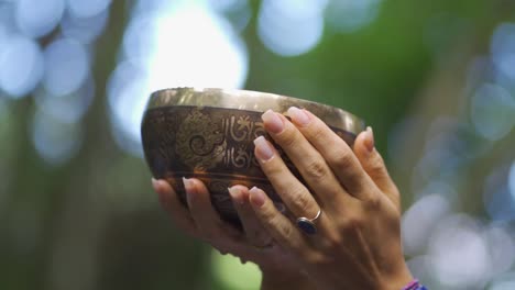 Close-up-of-a-person's-hand-carrying-a-brass-container-in-the-Salto-Encantado-park-located-in-Misiones,-Argentina