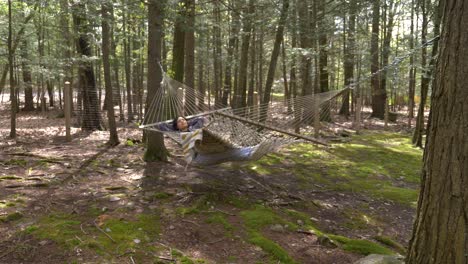 Lazy-young-female-swinging-in-woodland-hammock-enjoying-peaceful-dream-time-alone