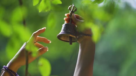 Close-up-of-woman's-hand-holding-a-bell-in-Salto-Encantado-park-located-in-Misiones,-Argentina