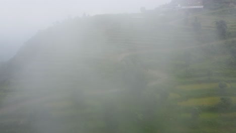 Aerial-shot-of-green-terraced-plantaiton-fields-on-slope-in-Nepal-during-Cloudy-day