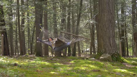 Comfortable-Puerto-Rican-female-swinging-in-woodland-hammock-enjoying-life-escape