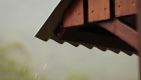 Close-shot-of-gentle-rain-on-a-tin-roof-with-a-timber-frame