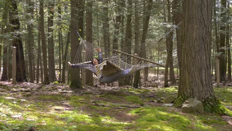 Young-adult-female-stretching-and-swinging-in-woodland-hammock-enjoying-relaxed-lifestyle