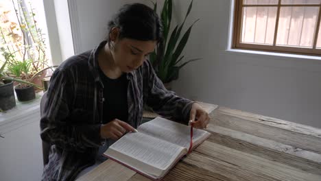Puerto-Rican-female-teenager-reading-and-studying-holy-bible-at-rustic-wooden-table