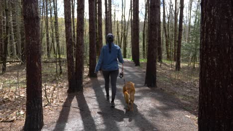 Active-healthy-Puerto-Rican-girl-walking-pet-dog-in-autumn-season-woodland-hiking-trail-footpath
