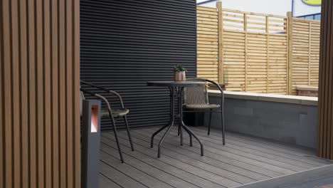 Wide-reveal-of-undercover-garden-entertaining-area-with-table-and-chairs-surrounded-by-grey-and-brown-cladding-outside-of-a-newly-built-luxury-garden-room