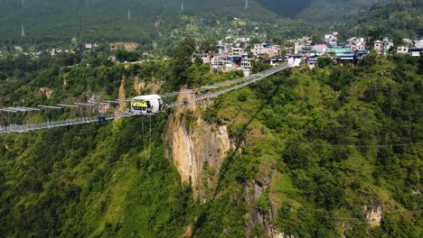Ascending-tilt-down-shot-showing-Suspension-bridge-and-bungee-jumping-spot-in-green-landscape-of-Nepal---Pokhara-City-in-background