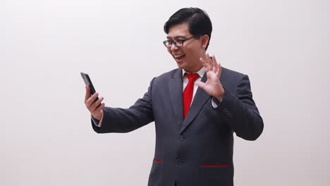 Aufgeregt-Asiatischer-Geschäftsmann,-Der-Videoanrufe-Per-Smartphone-Tätigt