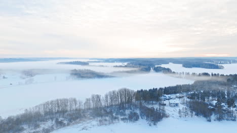 High-wide-shot-of-a-vast-nordic-scandinavian-landscape-with-forest-covered-in-snow-and-ice-and-fog-engulfing-the-beatiful-scenery