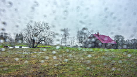 Time-lapse-of-rural-house-on-grass-field,-moving-clouds-during-day-over-rainy-drops-overlay
