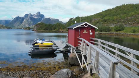 Jetty,-dinghy-boats-and-red-cottage-cabin-in-Tennstrand,-Lofoten-Islands,-Norway---Pan-Left