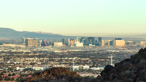 Las-Vegas-Strip-Skyline-Revealed-from-a-Rocky-Desert-Mountain,-Aerial