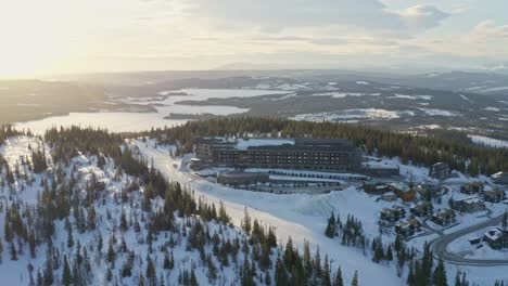Drone-aerial-view-over-Copperhill-Mountain-Lodge-in-Åre,-Sweden-during-sunset-and-winter