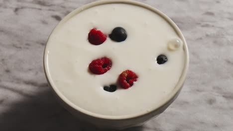 Müsli-Müsli-Fällt-In-Eine-Weiße-Schüssel-Mit-Joghurt-Auf-Dem-Hintergrund