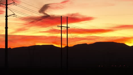 Silhouette-of-High-Tension-Power-Transmission-Lines-During-Sunset,-Aerial
