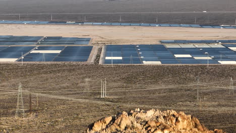 Solarpanel-Array-Auf-Einem-Solarpark-In-Der-Wüste,-Sichtbar-Hinter-Einem-Felsigen-Berg,-Luftaufnahme