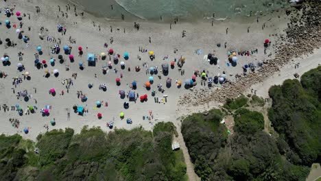 Dive-into-the-coastal-beauty-of-Llandudno-Beach,-Cape-Town,-with-daytime-drone-footage-over-vibrant-beach-umbrellas