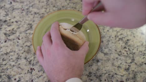 Blick-Von-Oben-Auf-Die-Hände,-Die-Einen-Englischen-Muffin-In-Zwei-Hälften-Schneiden,-Um-Ihn-Für-Ein-Gesundes-Und-Nahrhaftes-Frühstück-Zu-Toasten