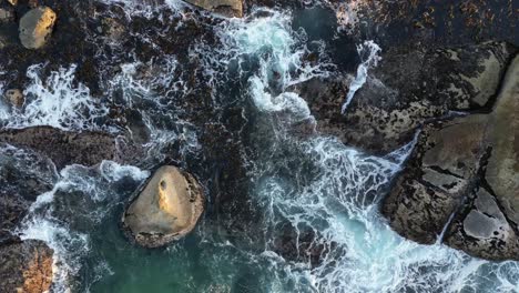 Experience-the-power-of-nature-with-drone-footage-capturing-waves-crashing-into-rocks-at-Bakoven-Beach,-Cape-Town,-South-Africa