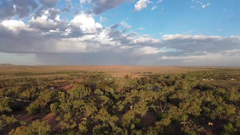 Sie-Fliegen-Rückwärts-über-Das-üppige-Outback-Und-Zeigen-Silverton,-New-South-Wales,-Australien,-Mit-Dunklen-Und-Stürmischen-Wolken-Im-Hintergrund