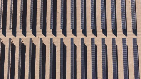 Rows-of-Solar-Panels-at-a-Solar-Farm-in-a-Desert-During-Daytime,-Aerial-Top-Down