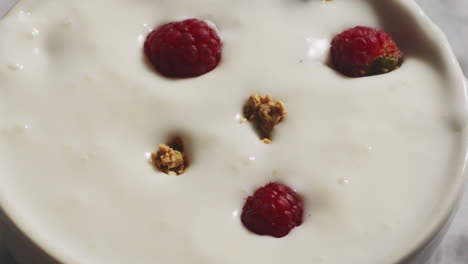 Granola-Cereals-and-berries-Falling-into-White-Bowl-Filled-with-yogurt