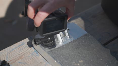 Man-hold-small-action-camera-and-stick-it-to-stunt-scooter-aluminum-deck
