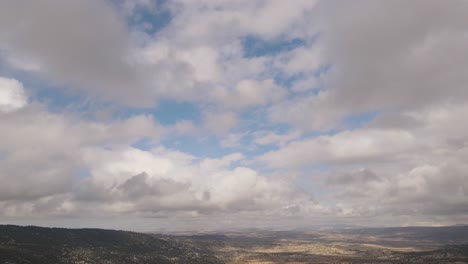 Mountain-landscape-shot-outdoors,-drone-view-of-time-lapse-clouds-moving-across-blue-sky