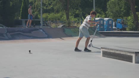 Un-Hombre-Con-Scooter-Acrobático-Realiza-Un-Truco-De-Deslizamiento-Y-Giro-De-180-Grados-En-El-Skatepark