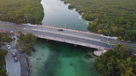 Aerial-descending-shot-overhead-people-diving-underneath-Punta-Nizuc-bridge