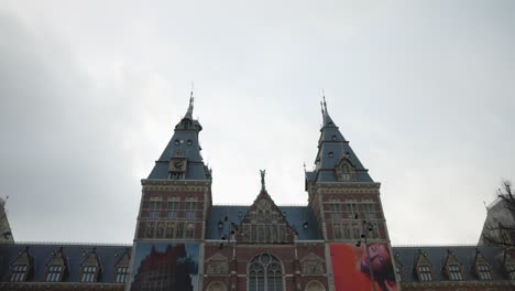 Front-Entrance-To-Rijksmuseum-On-Overcast-Day-With-Light-Traffic-Driving-Past