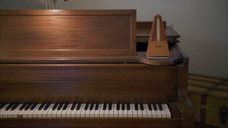 Ein-Antikes-Vintage-Metronom-Aus-Holz-Schwingt-Sein-Pendel-Mit-60-Schlägen-Pro-Minute-Auf-Einem-Alten,-Rustikalen-Braunen-Klavier