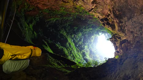 Vertical-shot-of-man-inside-Algar-do-Carvao-Volcanic-tube-in-Azores,-static