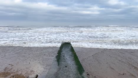 Concrete-groyne-on-Hendon-Beach-with-rough-North-Sea-waves-crashing-onto-the-sand