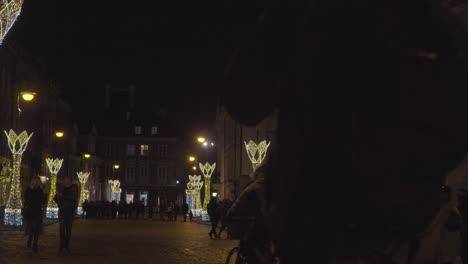 Christmas-Lighting-Decoration,-Old-Cobblestone-Streets-of-Old-Town-Warsaw-Poland-with-People-Walking-by