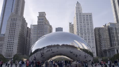 Los-Turistas-Se-Reúnen-Alrededor-De-La-Escultura-Reflectante-Cloud-Gate-En-Chicago,-Con-Los-Edificios-De-La-Ciudad-Altísimos.