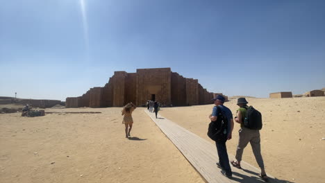 Tourists-walk-toward-Saqqara-Necropolis-building-in-Memphis