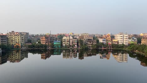 Rows-of-old-buildings-or-apartments-beside-a-pond-in-Kolkata,-India