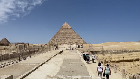 Tourists-walk-FORWARD,-TOWARD,-APPROACH-TO-GREAT-PYRAMID-OF-GIZA,-EGYPT