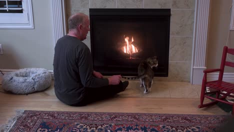 Old-senior-man-sitting-by-a-fireplace-with-his-cat